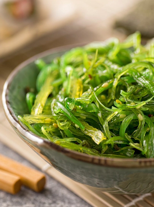 Μπολ με φρέσκο wakame, ιαπωνικό βρώσιμο φύκι με έντονο πράσινο χρώμα και λεπτές λωρίδες, έτοιμο για σερβίρισμα σε σαλάτες ή σούπες.