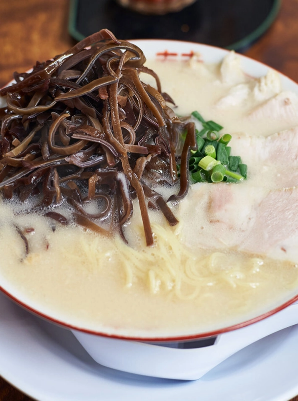 Μπολ με ramen σε πλούσιο ζωμό κοτόπουλου, γαρνιρισμένο με άφθονο kikurage (μανιτάρια wood ear), φρέσκο κρεμμυδάκι και λεπτές φέτες κοτόπουλου.