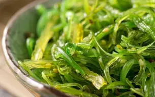 Μπολ με φρέσκο wakame, ιαπωνικό βρώσιμο φύκι με έντονο πράσινο χρώμα και λεπτές λωρίδες, έτοιμο για σερβίρισμα σε σαλάτες ή σούπες.